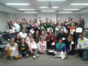 Large group posing indoors, many holding certificates and smiling.