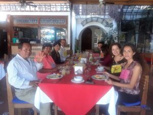 Family enjoying a meal together at a restaurant with a red tablecloth.