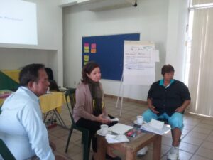 Three people engaged in a discussion in a classroom setting.